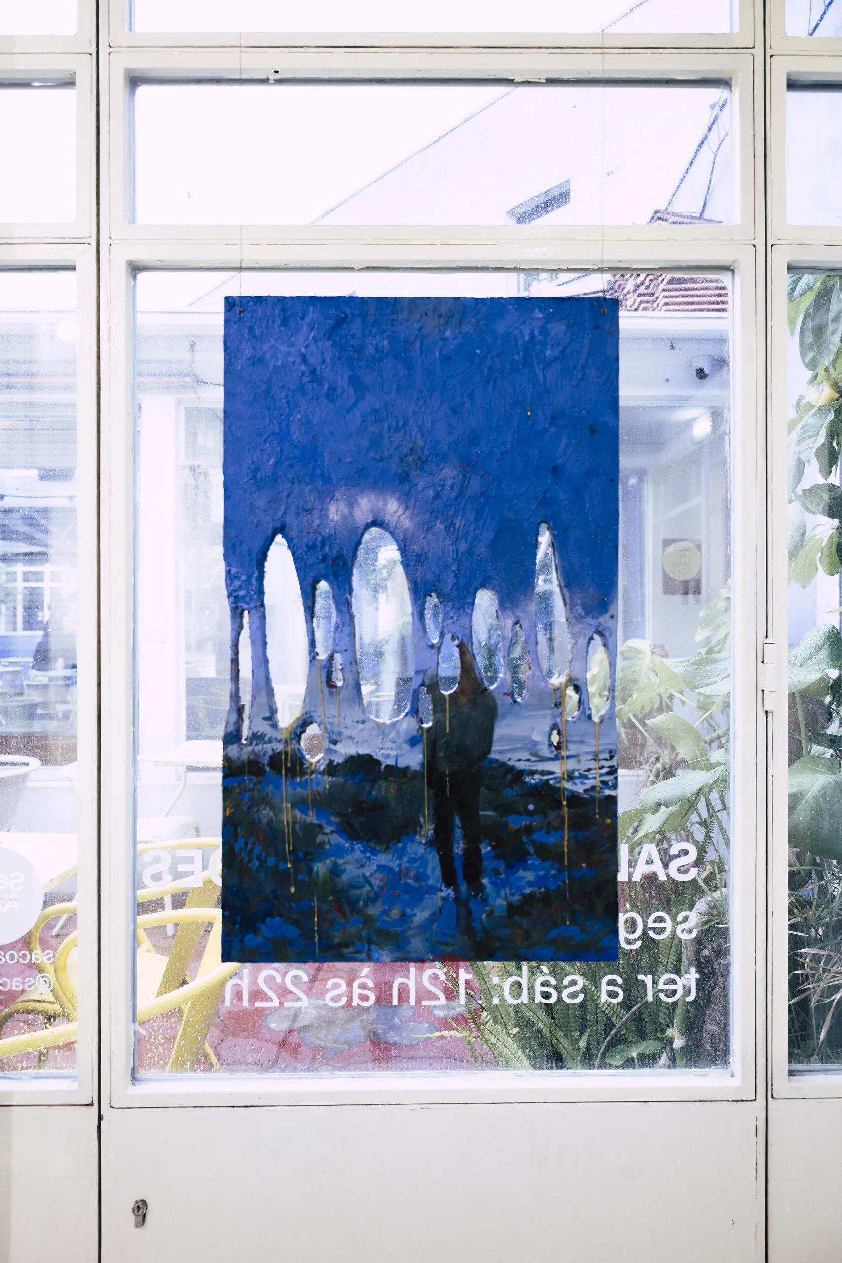 Espelho Meu: blue nocturnal painting with arches, hung in a window. Photo: Jenniffer Lima Pais