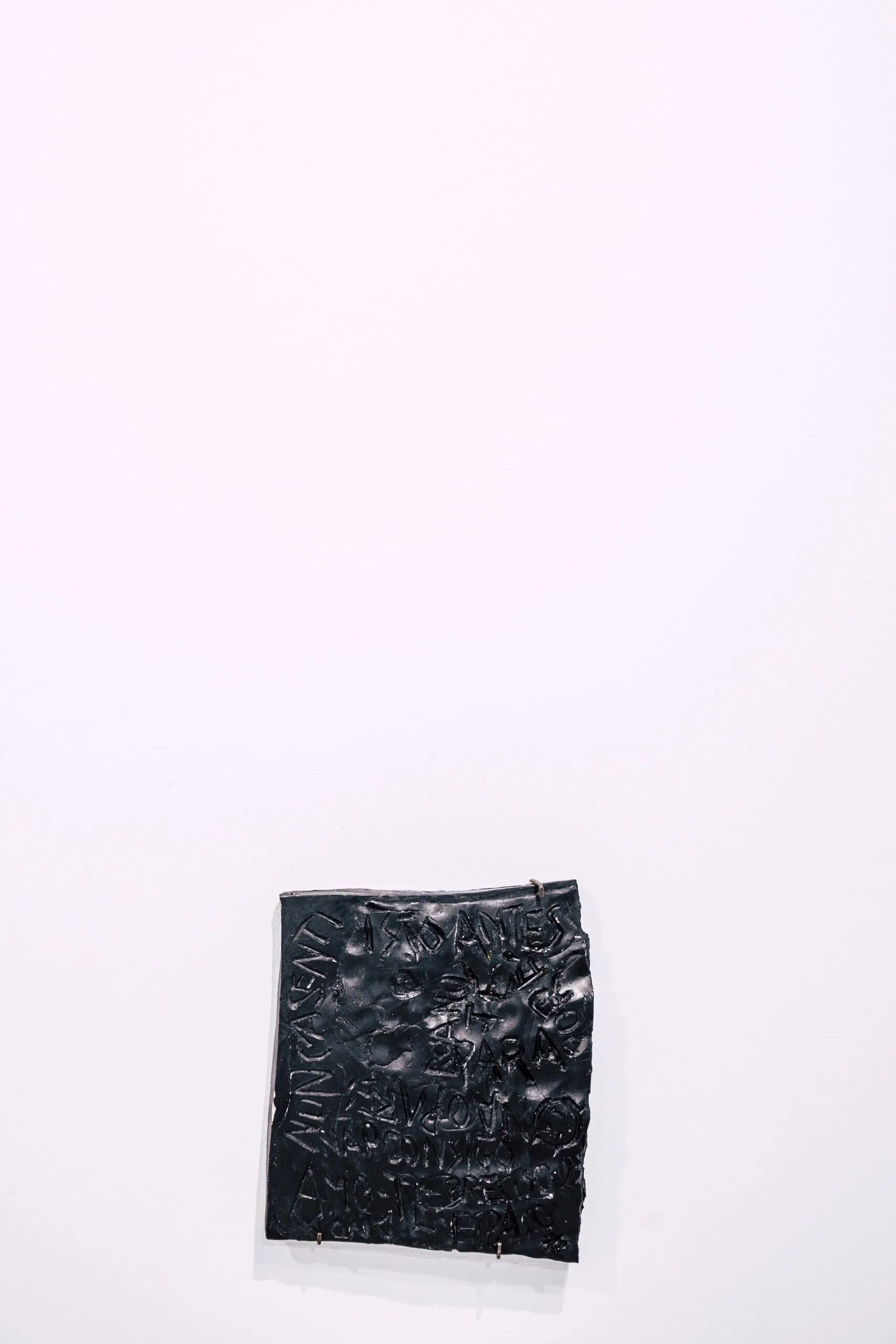 Espelho Meu: black textured square piece placed low on a white wall. Photo: Jenniffer Lima Pais