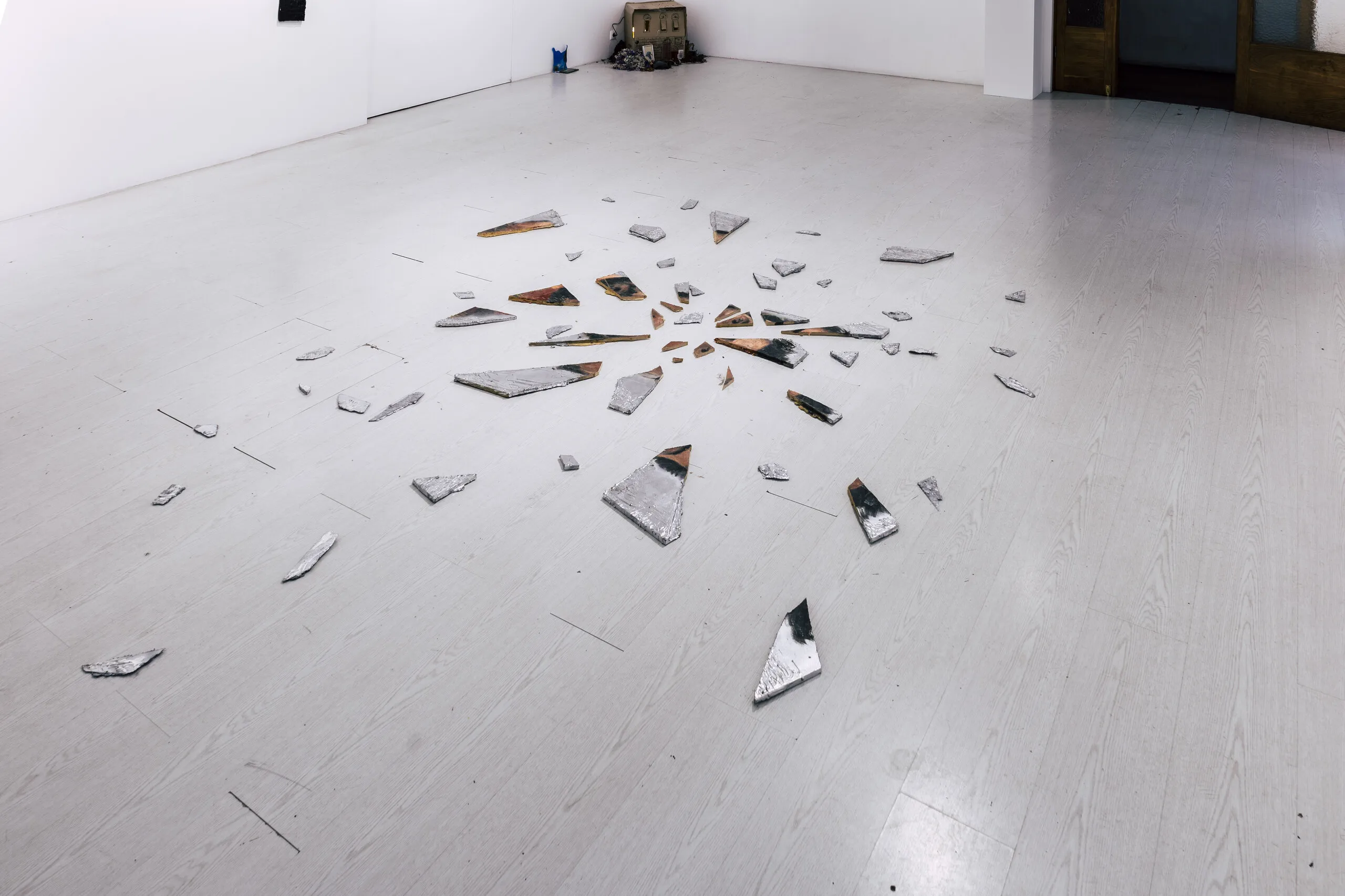 Espelho Meu, installation view: shattered mirror fragments arranged radially on the gallery floor. Photo: Jenniffer Lima Pais
