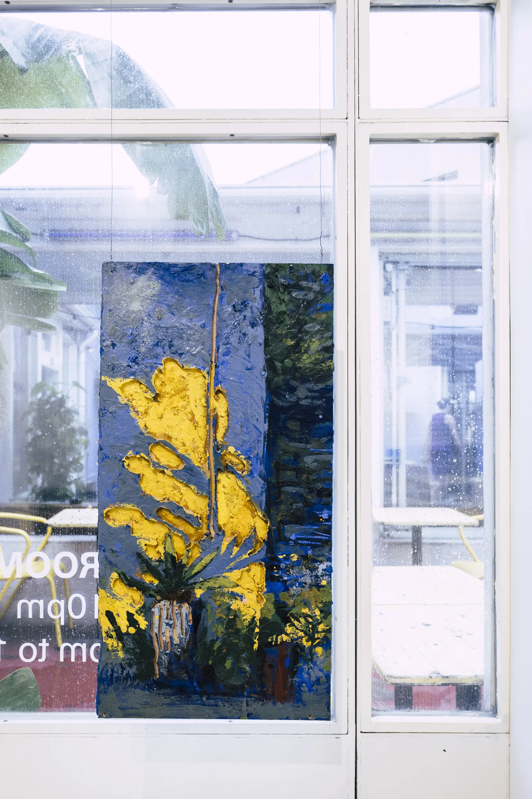 Espelho Meu: painted piece with yellow foliage hung against a window. Photo: Jenniffer Lima Pais