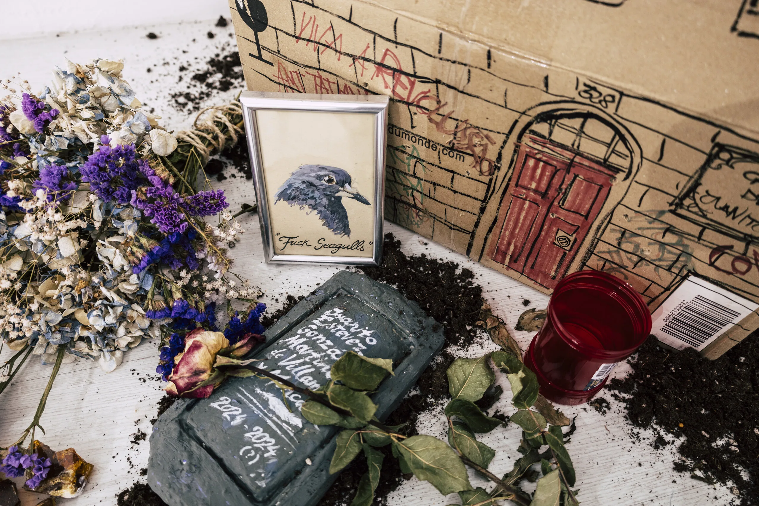 Espelho Meu, detail: dried flowers, soil, drawn door and a framed bird on the floor installation. Photo: Jenniffer Lima Pais