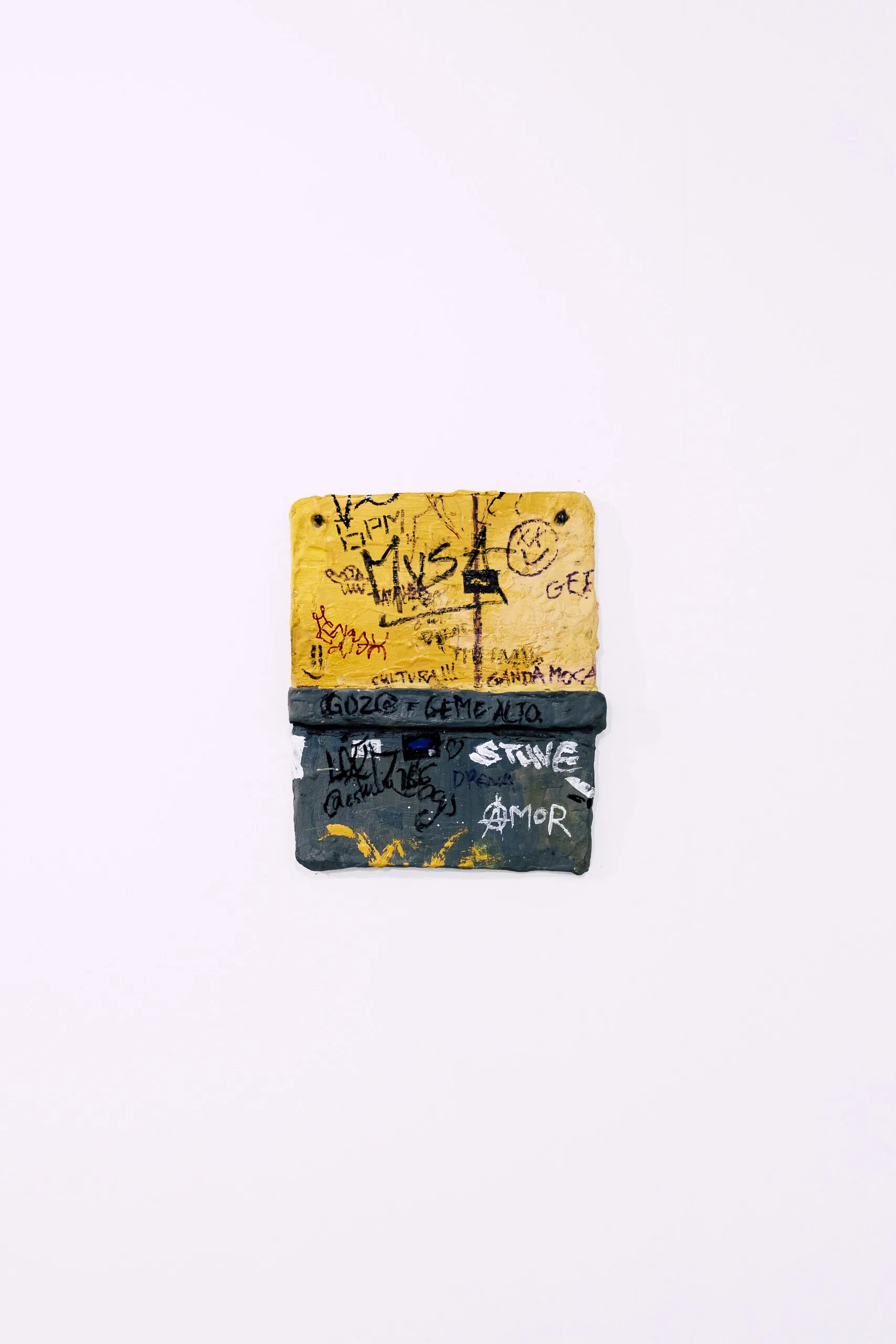 Espelho Meu: small yellow and black mixed-media piece on a white wall. Photo: Jenniffer Lima Pais